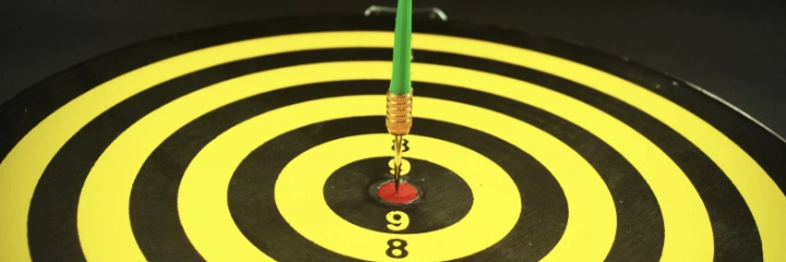 A dart board showing a dart in the bullseye
